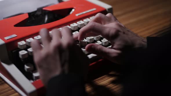 A Man in a Black Shirt Types Text on a Typewriter