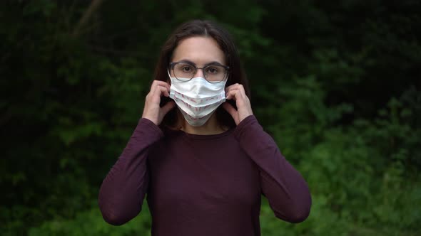 A Young Woman with Glasses Removes the Medical Mask with the Inscription Enough and Holds It Forward