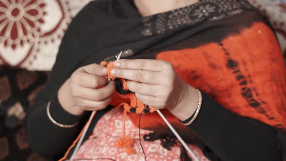 Old woman knitting with black and red wool and two needle crafts. Close up of knit work tie-up hand