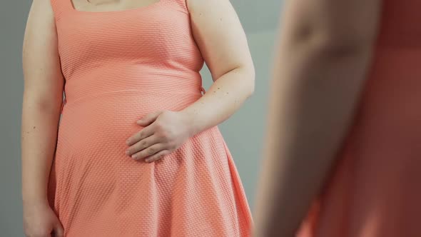 Overweight Female Standing in Front of Mirror, Touching Fat Stomach and Sobbing