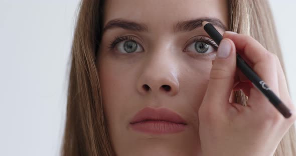 Young Woman Using Eyebrow Pencil Doing Makeup