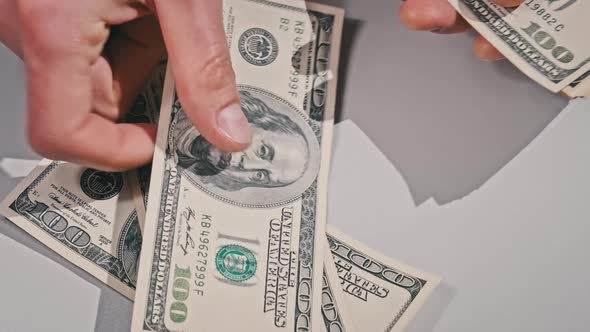 Male Hands Counting Old Hundred Dollar Banknotes on a White Table