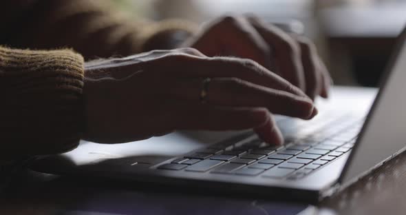 Man's Hands Typing Text on Laptop Keyboard at Wooden Desk