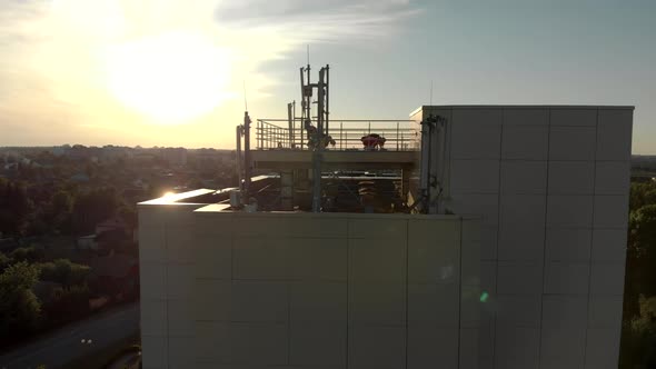 Group of People Exercise on the Roof of a Building While Stretching at Sunset