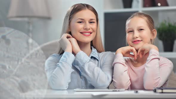 Beautiful Mother Posing with Teen Daughter Smiling Looking at Camera Relaxing During Making Homework