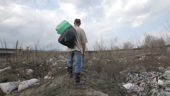 Homeless Man Standing on Garbage Hill at Dump Site