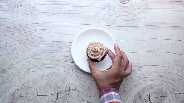 Man Hand Putting Chocolate Cup Cake on a Plate 