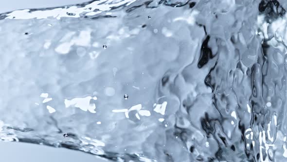 Super Slow Motion Detail Shot of Water Stream on Light Blue Background at 1000Fps