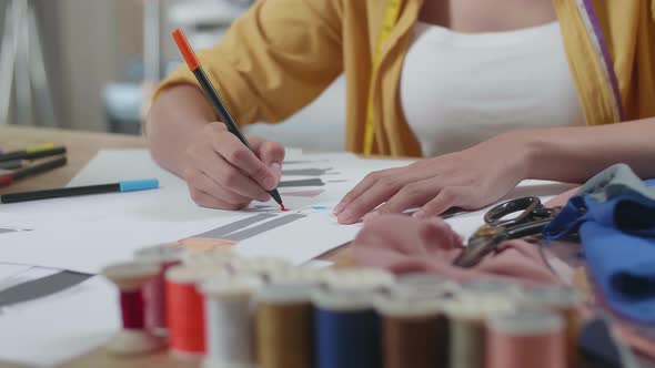 Close Up Of Female's Hand Designing Clothes On The Paper In The Studio