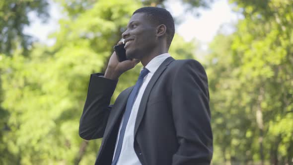 Portrait of Confident African American Man in Suit Talking on the Phone While Noticing Camera