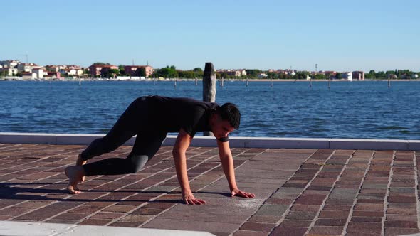 Ballet Dancer Performs Moves on Paved Embankment in Summer