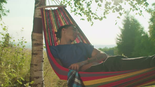 Relaxed Attractive Arab Male Tourist Napping in Hammock in Mountains at Daybreak