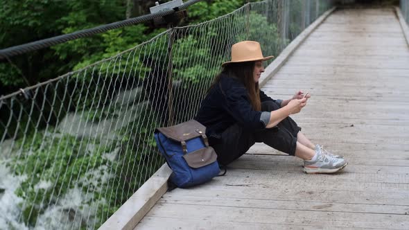 Hipster woman traveler in hat passively scrolling through social media or editing photos videos