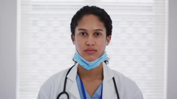 Portrait of mixed race female doctor putting a face mask on