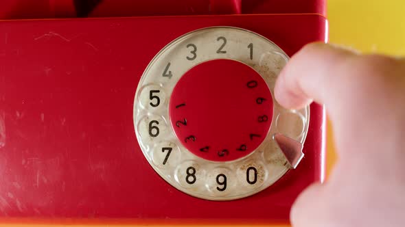 Close Up Man Hand Dialing on Old Vintage Red Dial Telephone Number 911