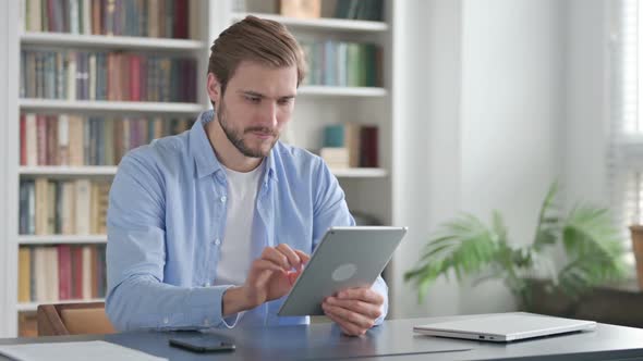 Man Celebrating Success on Tablet in Office