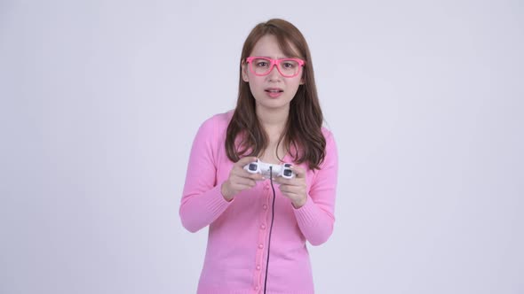 Young Happy Asian Nerd Woman Playing Games and Winning