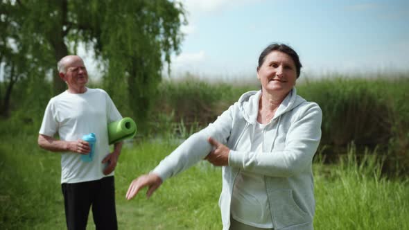 Health Care, Old Pretty Woman Practices and Performs Hand Exercises Background of Husband Drinking