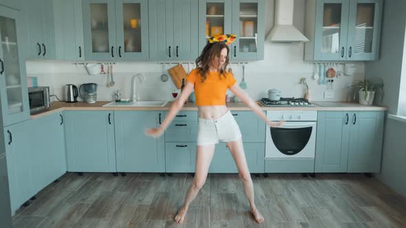 A Beautiful Woman in White Shorts is Relaxing at Home Dancing in the Kitchen