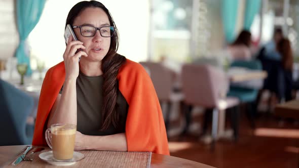 Businesswoman is Calling By Mobile Phone During Coffee Break in Cafe Resting with Cup of Latte