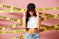 Dark-haired girl in pink sunglasses and cap dressed in jeans shorts and white top keeps her hands on - PhotoDune Item for Sale
