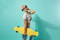 Funny young girl in sunglasses and pink bow on her head dressed in jeans and top stands with yellow - PhotoDune Item for Sale