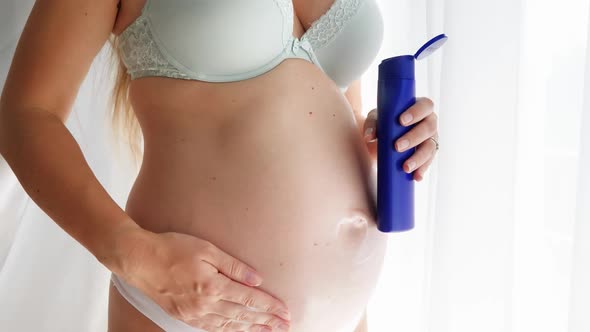 Closeup of Pregnant Woman in Bra and Panties Applying Creme on Her Body and Taking Care of Her Skin