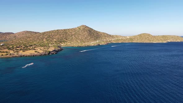 Aerial View of a Speeding Motor Boat in a Deep Blue Colored Sea. Spinalonga Island, Crete, Greece