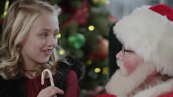 Little girls eyes light up as Santa Claus hands her a candy cane