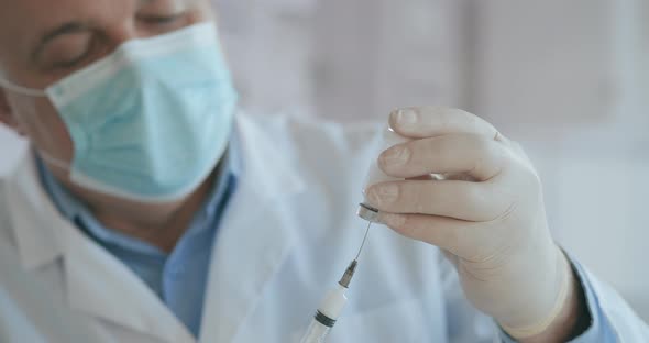 Doctor Hand Holds a Syringe and a Blue Vaccine Bottle at the Hospital. Health and Medical Concepts