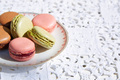 Macarons biscuits with ceramic saucer and white embroidered tablecloth in sunlight - PhotoDune Item for Sale