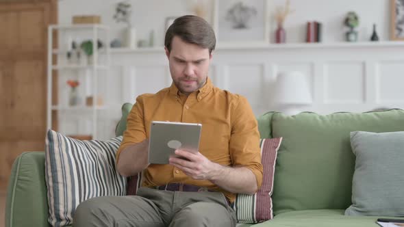 Young Man using Tablet on Sofa