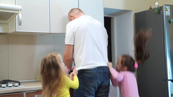 Girls Bothering Man Washing Dishes in Kitchen