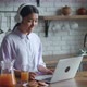 Young Cheerful Asian Woman Sitting Kitchen Table at Laptop Computer and Talking to Friend Online - VideoHive Item for Sale