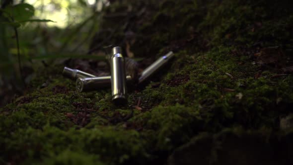 Bullet casings fall on the moss. Shooting in the forest. Slow motion. alt