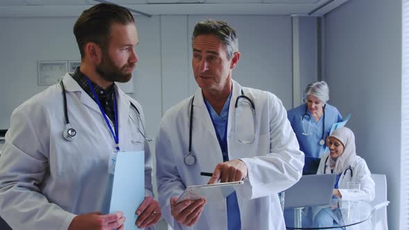 Front view of Caucasian male doctors discussing over digital tablet at hospital