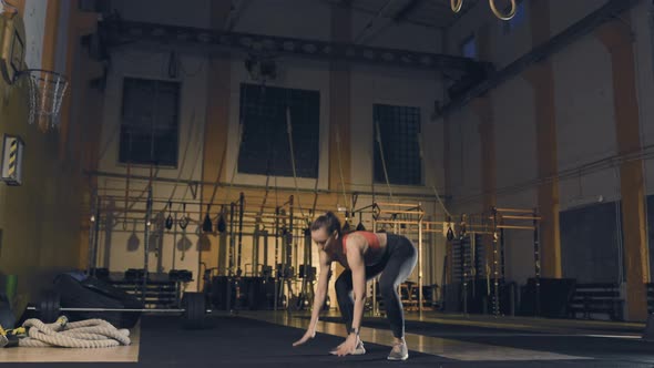 Young Woman Doing Burpee in Gym