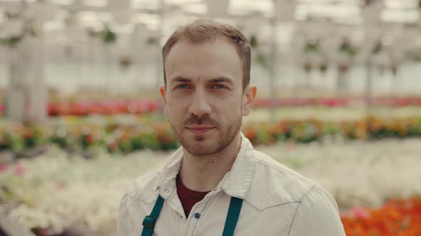Portrait of the Male Gardener Looking at the Camera and Smile on the Flory Background