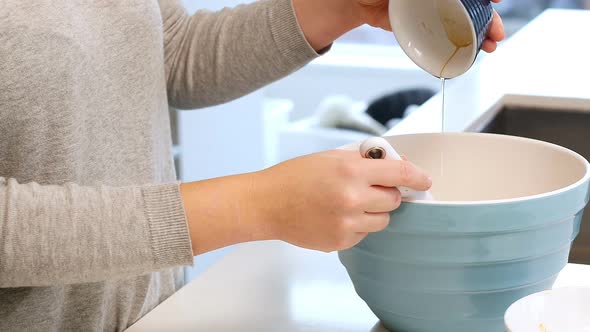 Woman adding ingredients to bowl for baking