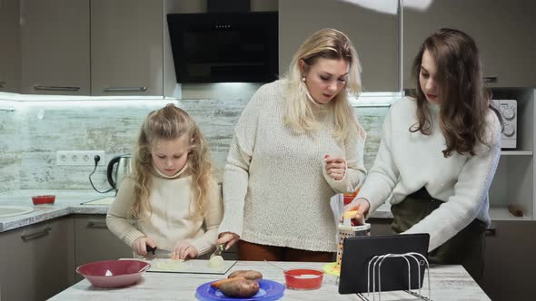 Young Mother and Two Her Daughters Cooks Salad at Kitchen