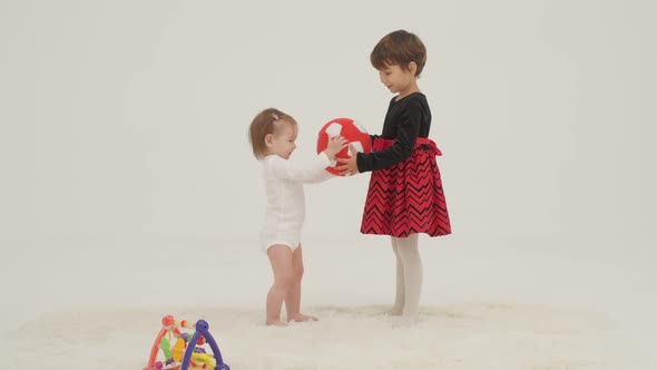 Two Little Girls Playing Toys in a White Room