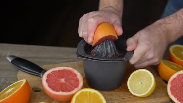 A Man Squeezes Orange Juice with Citrus Juicer