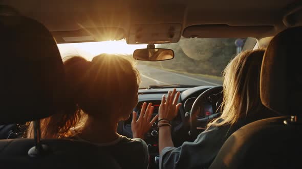 Rear View of Cheerful Young Girlfriends Singing Their Favourite Song and Dancing While Driving at