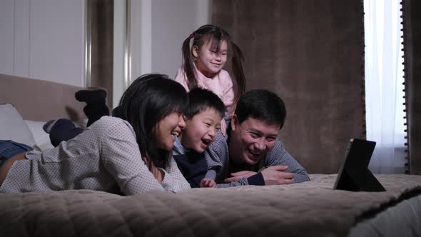 Laughing Asian Family Watching Comedy on Tablet Pc