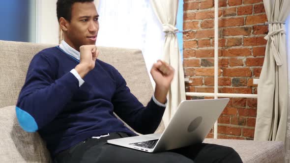 African Man Enjoying Listening Music on Laptop Relaxing at Home