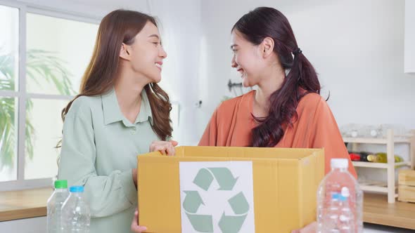 Portrait of Asian woman put plastic bottles into recycle box, hold trash bin for further recycling.