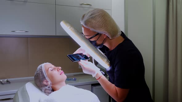 Female Doctor Photographs the Result of Her Work on a Mobile Phone. Lip Augmentation Procedure with