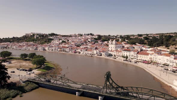 Lifting bridge over river Sado with majestic skyline view of Alcacer Do Sal town, aerial