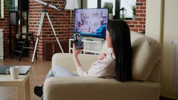 Young Adult Woman Having Online Conversation on Smartphone with Manager While Working From Home