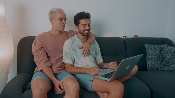 Gay Couple Shopping Online Using Laptop and Credit Card